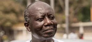This is a close-up photograph of Ken Ofori-Atta, likely related to a news story about his case being pushed to April in a US court. His face is the primary subject, and he appears to be looking slightly to the side. The background is blurred.