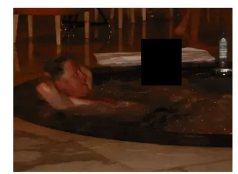 US Department of Justice Former President Bill Clinton lays in a hot tub. Sitting next to him is a person whose face has been redacted
