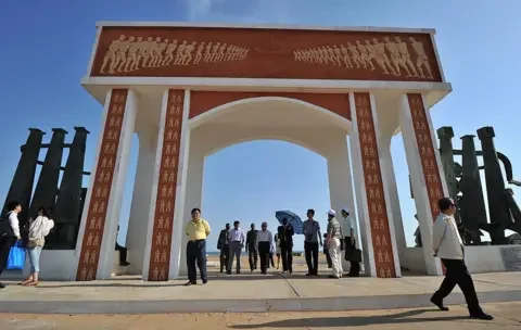 AFP via Getty Images People stand under and around the door of no return