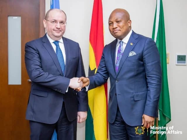 A photograph showing a formal handshake between a foreign official and Ghanaian politician Samuel Okudzeto Ablakwa. The meeting takes place in front of the Ghanaian flag and a green flag, suggesting a diplomatic engagement at a government office.