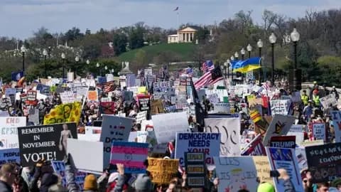 Getty Images A sea of people hold up signs as they march. All the signs are against the Trump administration and key policies