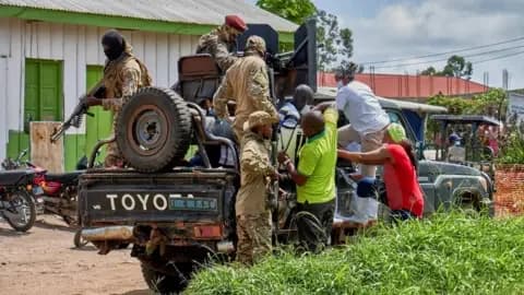 Reuters Medical staff climb aboard a military vehicle on the grounds of Rwampara General Hospital. One soldier pictured in camouflage has a large machine gun.