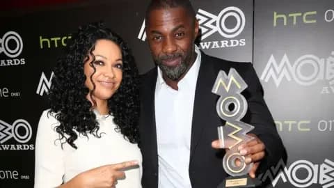 PA Media Kanya King and Idris Elba standing together, she's pointing at him and he's holding a Mobo trophy