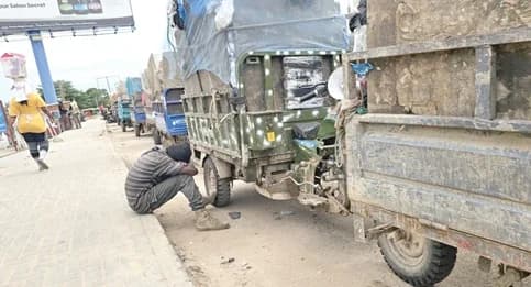 A tricycle rider taking a nap as hundreds of refuse carriers queue to access the dumping site
