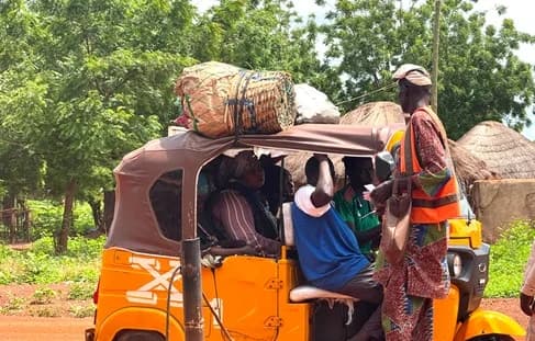 A revenue officer of the Tolon District Assembly taking a toll from trycicle operators at the entrance of the market