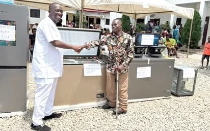Kalamu Musah Adamu (left), MCE for Ablekuma North, presenting one of the items to a beneficiary