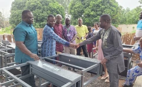 Francis Akumatey Addo (2nd from left), Municipal Chief Executive, Yilo Krobo, presenting the furniture to John Kwame Gasu (right), the Yilo Krobo Education Director