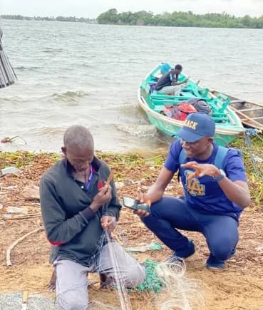 Daily Graphic's Timothy Ngnenbe interacting with Noah Aggrey as he mends his net at the shores of Azizape Island.