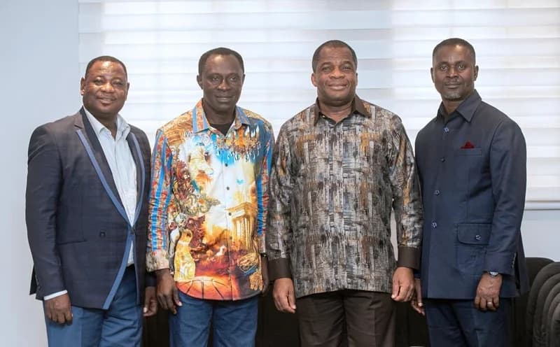 A group photograph featuring four men standing indoors against a backdrop of white window blinds. Rev. Stephen Wengam, the General Superintendent of Assemblies of God, Ghana, is positioned second from the right among the group.