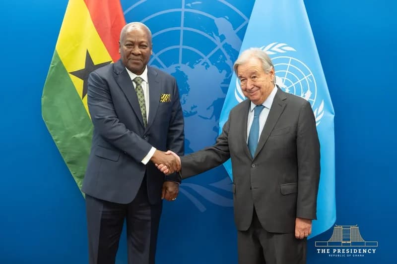 President John Mahama and UN Secretary-General António Guterres are seen shaking hands during an official diplomatic meeting. The scene is set against a blue backdrop with the UN emblem, flanked by the national flag of Ghana and the UN flag.