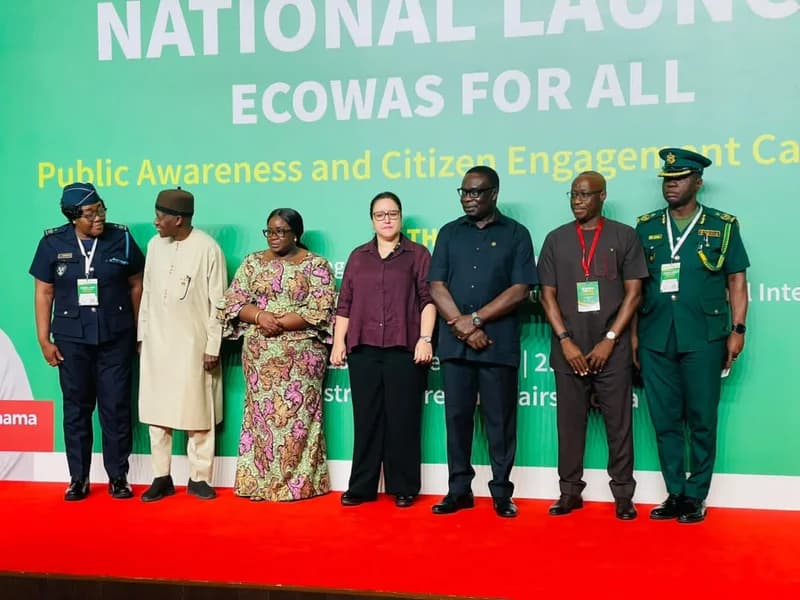 Seven officials representing various sectors stand together on a red carpet during the national launch of the 'ECOWAS for All' campaign in Ghana. Behind them, a large green backdrop features white and yellow text announcing the public awareness and citizen engagement initiative.