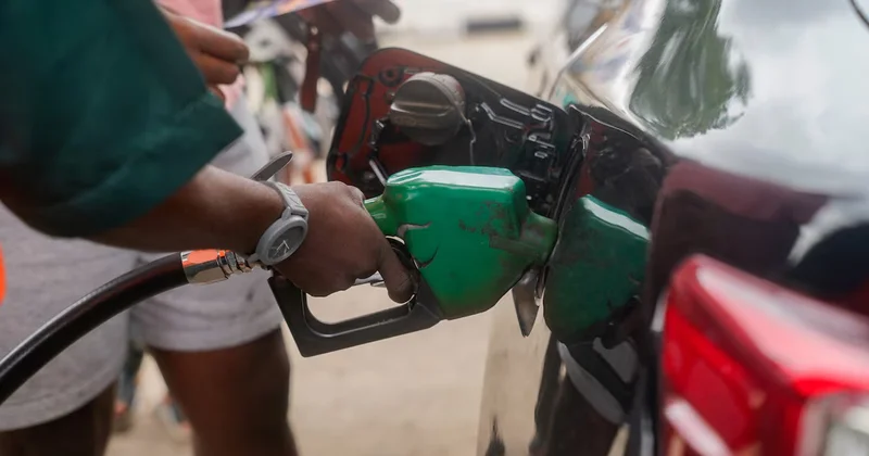 A close-up photograph shows a person refueling a vehicle at a gas station, with a green fuel nozzle inserted into the tank. This image illustrates the downstream energy sector and domestic fuel consumption, reflecting the article's theme on gas supply growth.