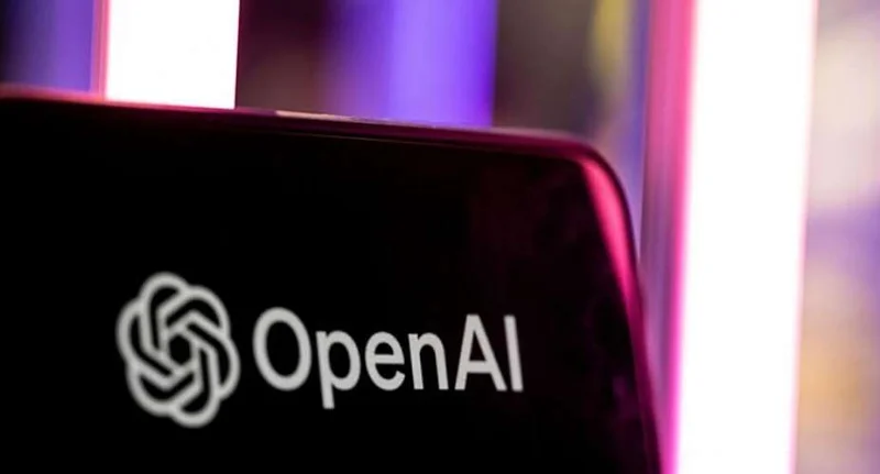 A close-up photograph of a smartphone screen displaying the white OpenAI logo and brand name. The background is softly blurred with vertical neon light tubes in shades of purple and pink, creating a contemporary tech-focused atmosphere.