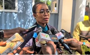 Dr. Zanetor Agyeman-Rawlings, MP for Korle Klottey, is captured during a media interview. She is surrounded by journalists holding various microphones, including those from GTV and Adom TV, as she addresses the press about government-related matters.
