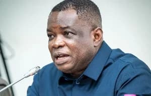 A close-up photograph of Kwasi Amoako-Attah, Ghana's former Minister for Roads and Highways, speaking into a microphone. He appears to be addressing an audience at an official government function or press conference.