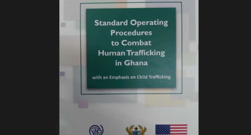A photograph of a document cover titled 'Standard Operating Procedures to Combat Human Trafficking in Ghana with an Emphasis on Child Trafficking'. The page features the Ghana Coat of Arms and the United States flag at the bottom, signifying bilateral cooperation on human rights issues.