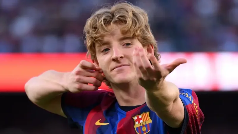A close-up shot of Anthony Gordon celebrating in an FC Barcelona jersey. The player is seen gesturing with his hands following a goal, with the club's crest and sponsor logo clearly visible on his kit.