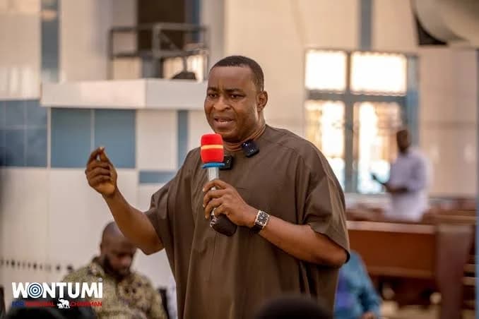 Bernard Antwi Boasiako, popularly known as Chairman Wontumi, is captured speaking into a microphone while wearing a brown traditional smock. The image appears to be from a political or public event, featuring a watermark at the bottom left.