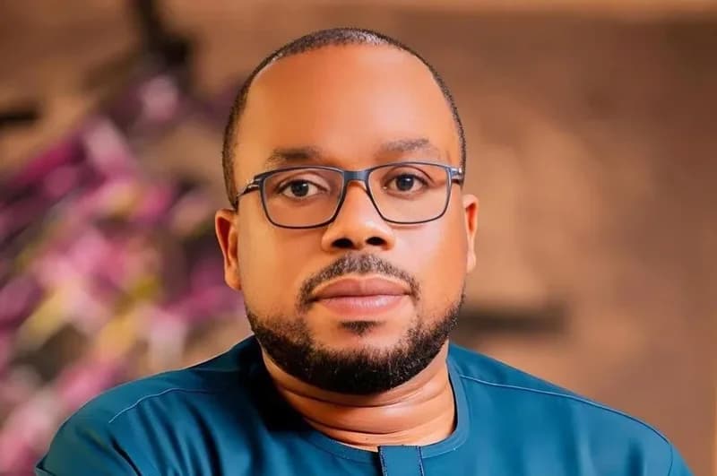 A close-up portrait of Samuel Okudzeto Ablakwa, a prominent Ghanaian politician and Member of Parliament. He is shown wearing glasses and a teal-colored shirt against a blurred, warm-toned background.